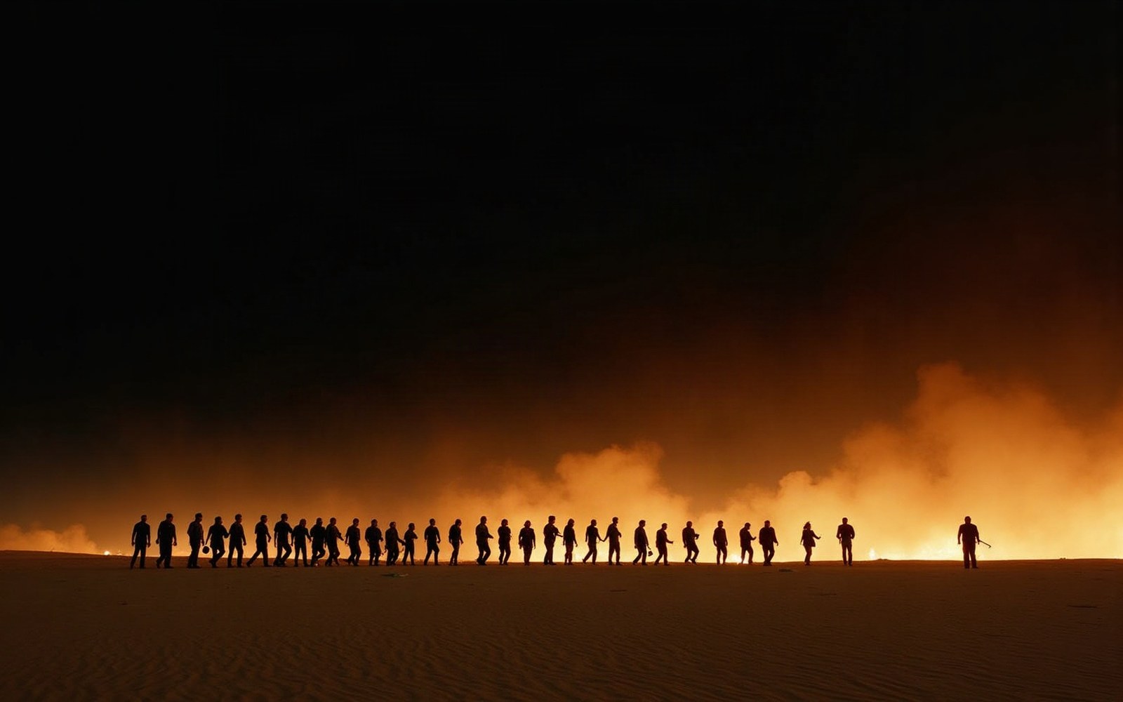 Silhouetted figures walk in a line across the desert against a fiery orange horizon