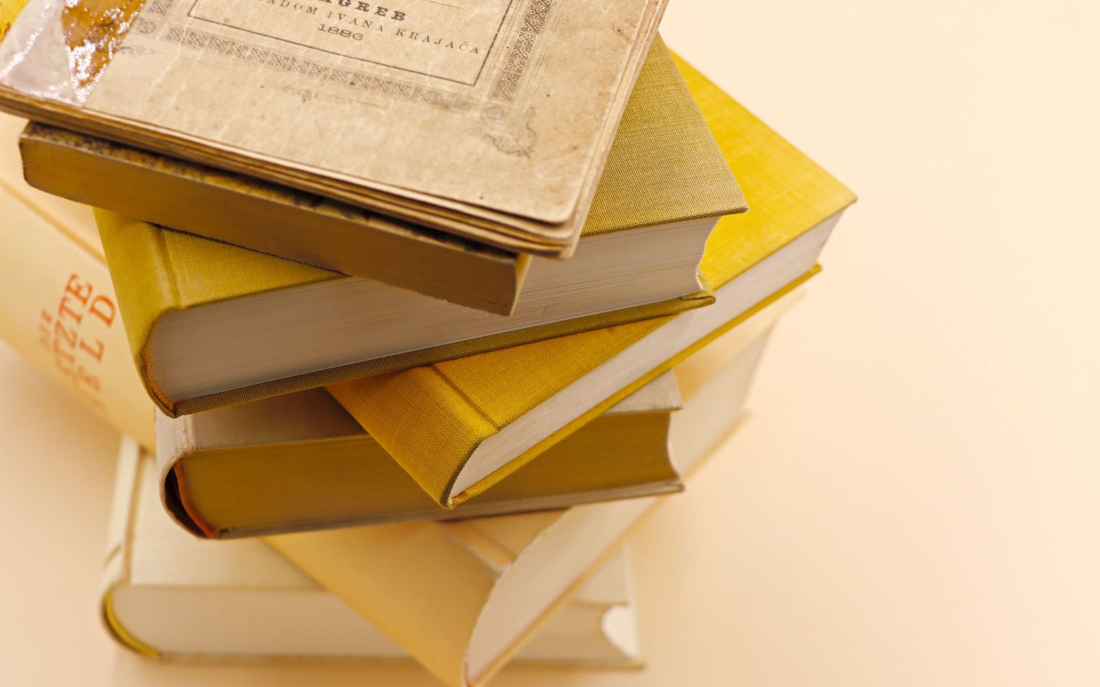 Stack of yellow hardcover books topped with a worn, aged softcover book